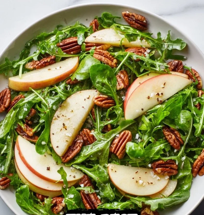 Delicious Apple Arugula Salad topped with Maple Pecans in a bowl.