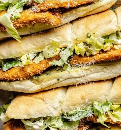 Delicious Chicken Caesar Sandwiches on a plate garnished with fresh herbs.