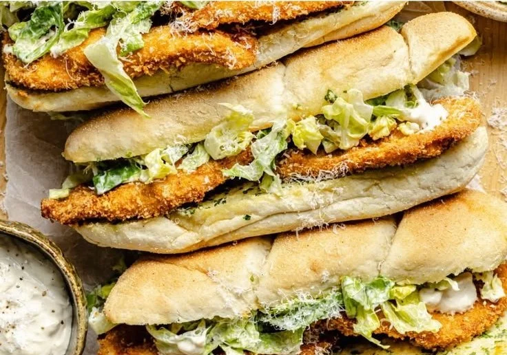 Delicious Chicken Caesar Sandwiches on a plate garnished with fresh herbs.