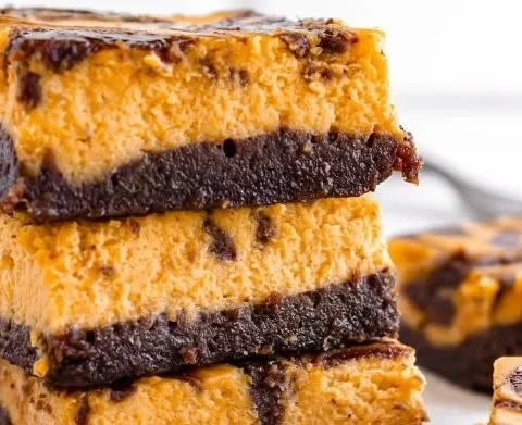 Delicious creamy pumpkin cheesecake brownies topped with whipped cream.