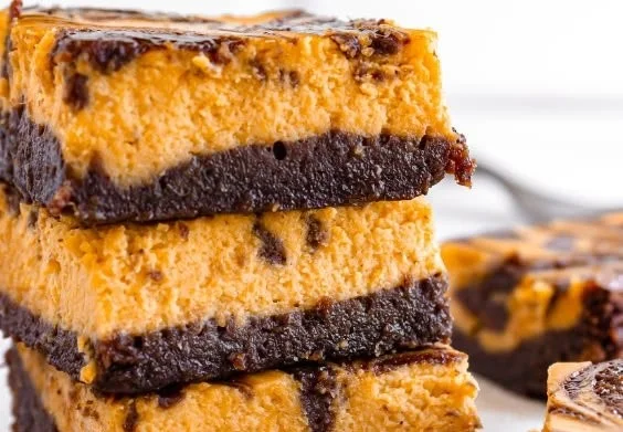 Delicious creamy pumpkin cheesecake brownies topped with whipped cream.