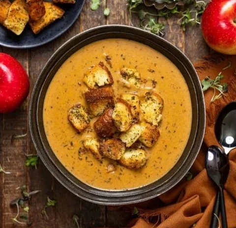 Bowl of creamy roasted apple pumpkin soup garnished with herbs