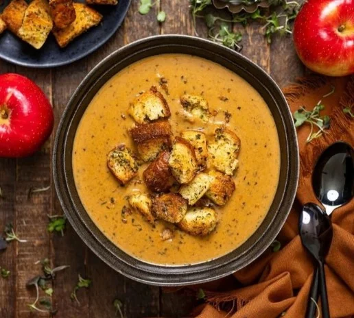 Bowl of creamy roasted apple pumpkin soup garnished with herbs