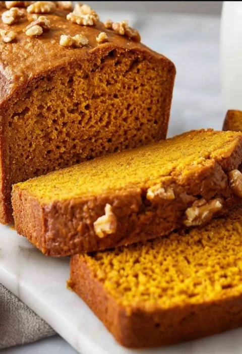 Slice of healthy pumpkin bread on a rustic table with fall decor.