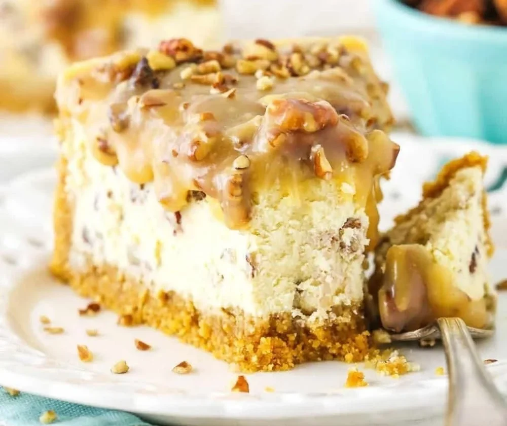 Slice of decadent Pecan Praline Cheesecake topped with pecans and caramel