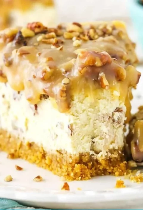 Slice of decadent Pecan Praline Cheesecake topped with pecans and caramel