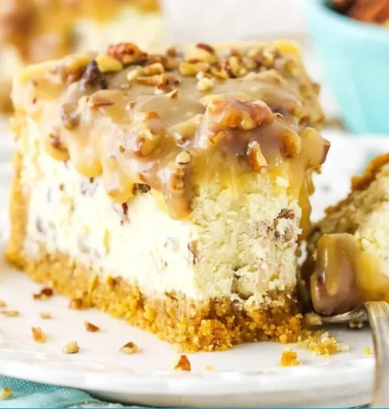 Slice of decadent Pecan Praline Cheesecake topped with pecans and caramel