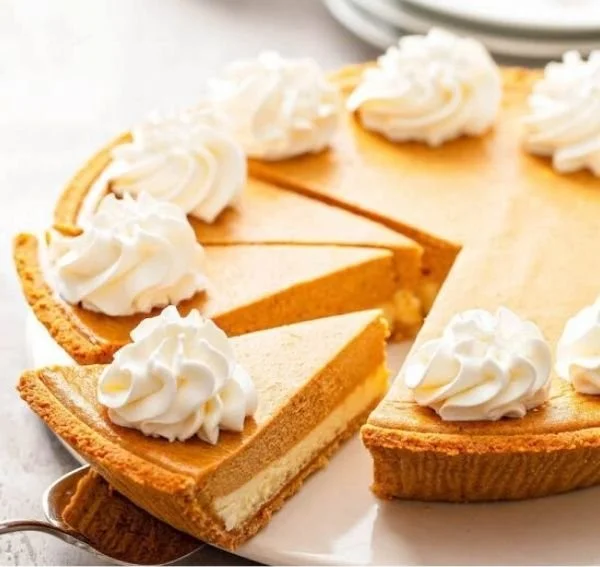 Slice of pumpkin pie cheesecake topped with whipped cream and spices