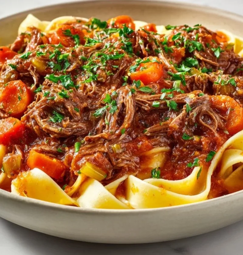 Delicious slow cooker beef ragu served over pasta with fresh herbs.