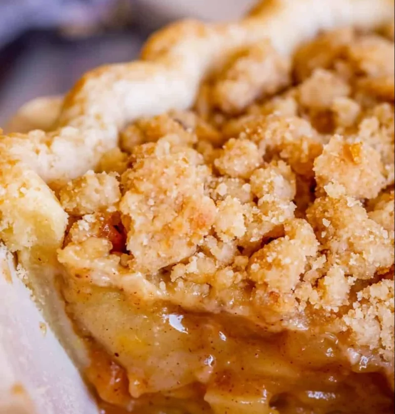 Delicious slice of Dutch apple pie with all-butter crust on a wooden table