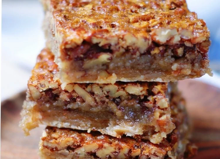 Delicious homemade pecan pie bars on a plate with nuts