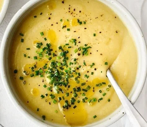 Creamy potato leek soup garnished with fresh herbs in a bowl