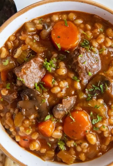 Bowl of easy beef barley soup with vegetables and herbs