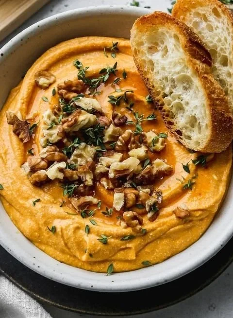 Pumpkin Whipped Feta Dip served in a bowl with herbs and crackers