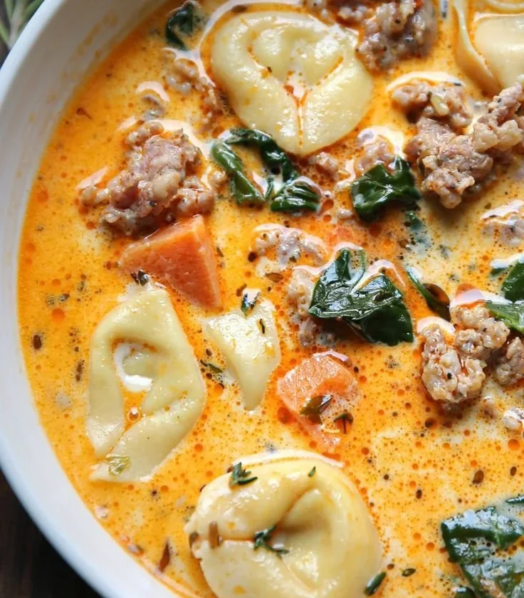 Bowl of Sausage Tortellini Soup with Spinach, garnished with parmesan cheese.
