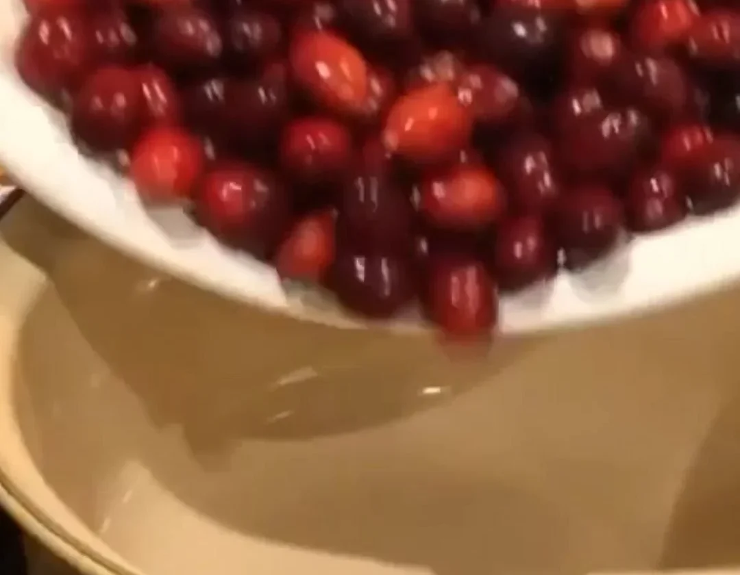Homemade cranberry sauce served in a bowl with fresh cranberries and herbs